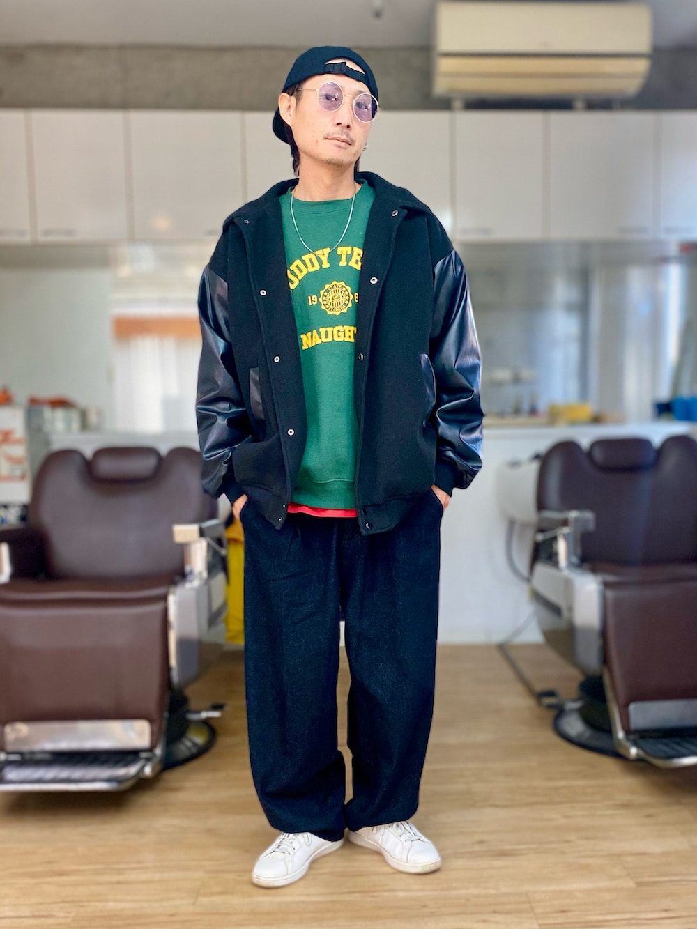 グリーン系のスウェット、ブラック系のスタジャン、ブラック系のデニムパンツを着用したメンズの冬コーディネートの3枚目の写真