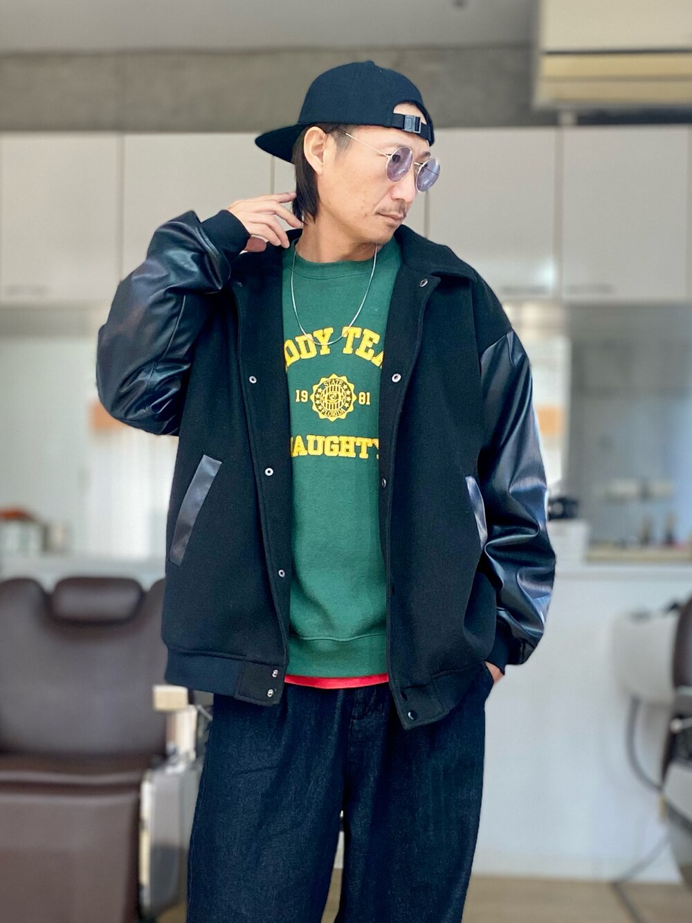 グリーン系のスウェット、ブラック系のスタジャン、ブラック系のデニムパンツを着用したメンズの冬コーディネートの4枚目の写真