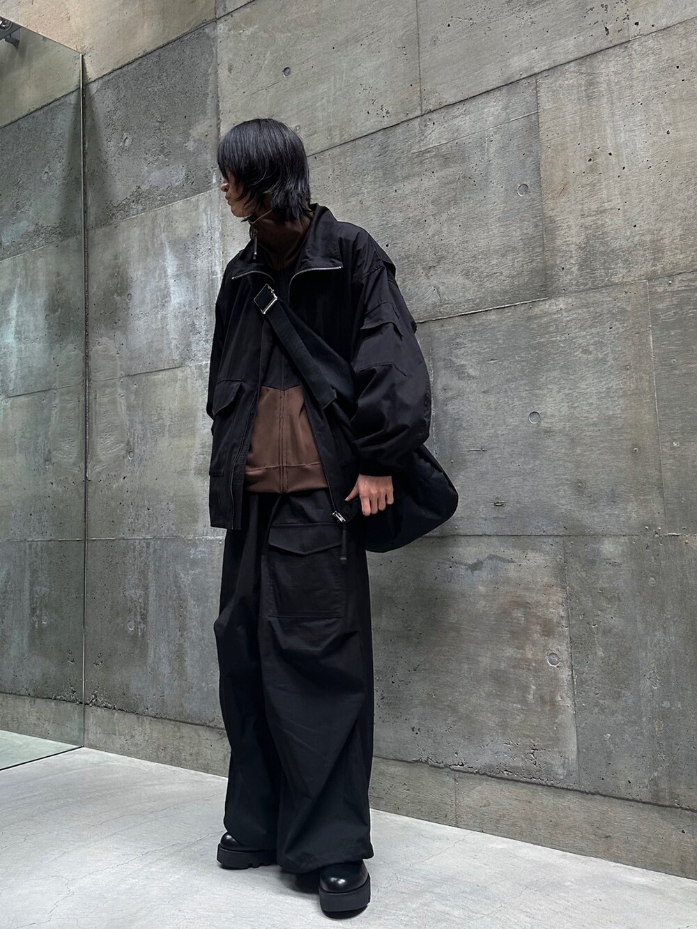 ブラック系のミリタリージャケット、ブラック系のブーツ、ブラック系のショルダーバッグを着用したメンズの春コーディネートの3枚目の写真