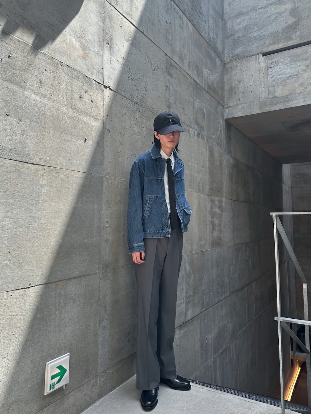 ブルー系のデニムジャケット、グレー系のスラックス、ブラック系のネクタイを着用したメンズの春コーディネートの3枚目の写真