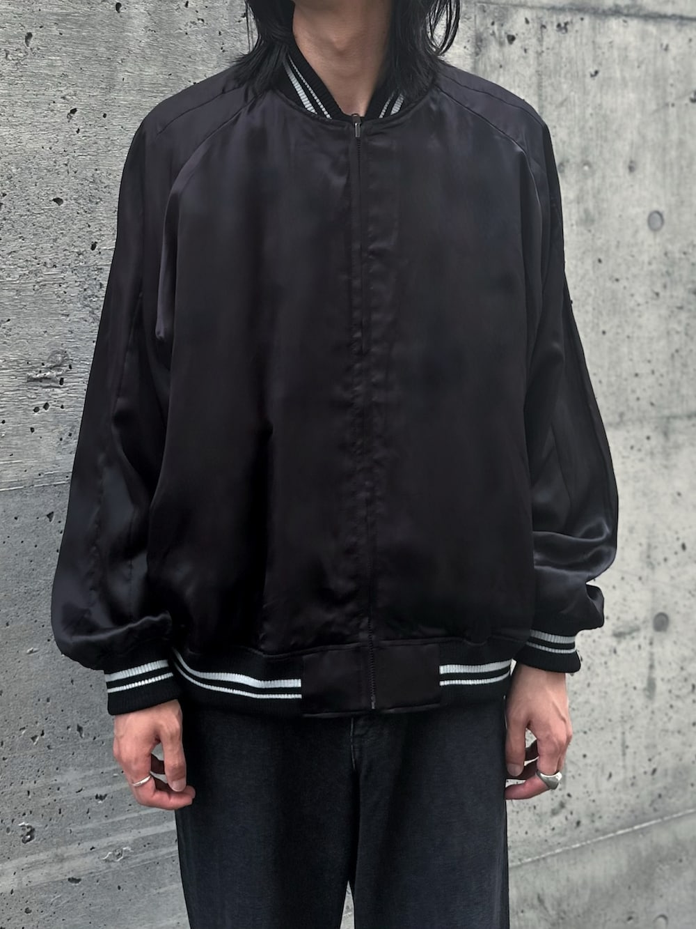 ブラック系のローファー、ブラック系のスカジャン、グレー系のデニムパンツを着用したメンズの秋コーディネートの3枚目の写真