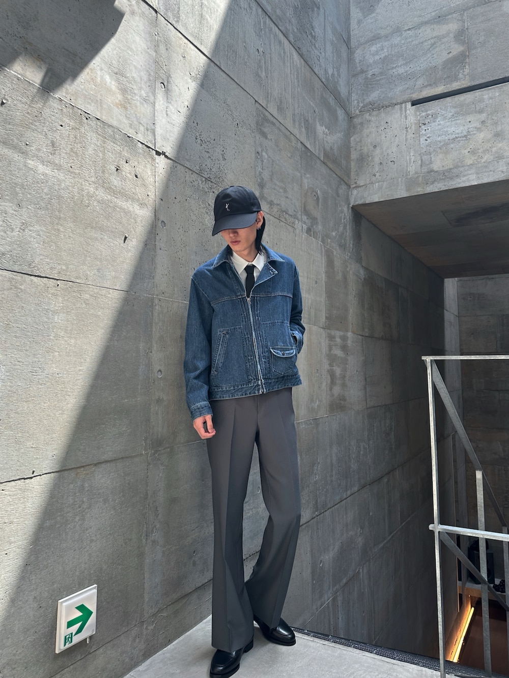 ブルー系のデニムジャケット、グレー系のスラックス、ブラック系のネクタイを着用したメンズの春コーディネートの2枚目の写真