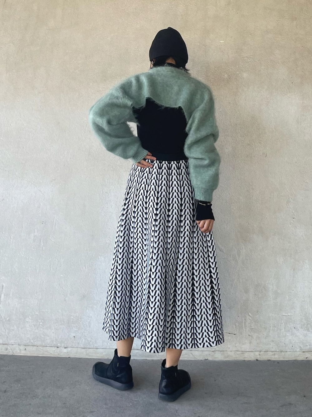 グリーン系のニット/セーター、ホワイト系のスカート、ブラック系のブーツを着用したレディースの冬コーディネートの4枚目の写真