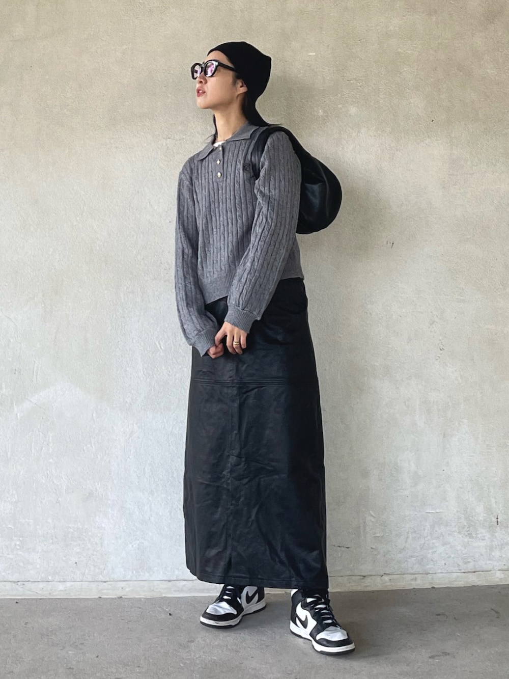 グレー系のニット/セーター、ブラック系のスカート、ホワイト系のスニーカーを着用したレディースの秋コーディネートの3枚目の写真