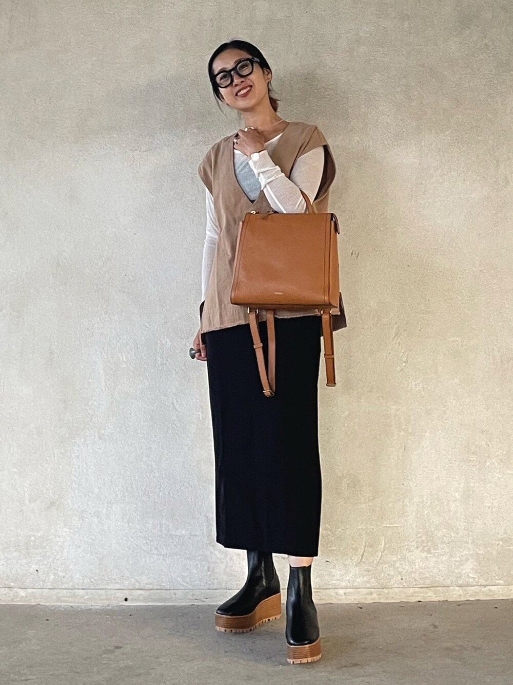 ベージュ系のベスト、ホワイト系のTシャツ/カットソー、イエロー系のバックパック/リュックを着用したレディースの秋コーディネートの2枚目の写真