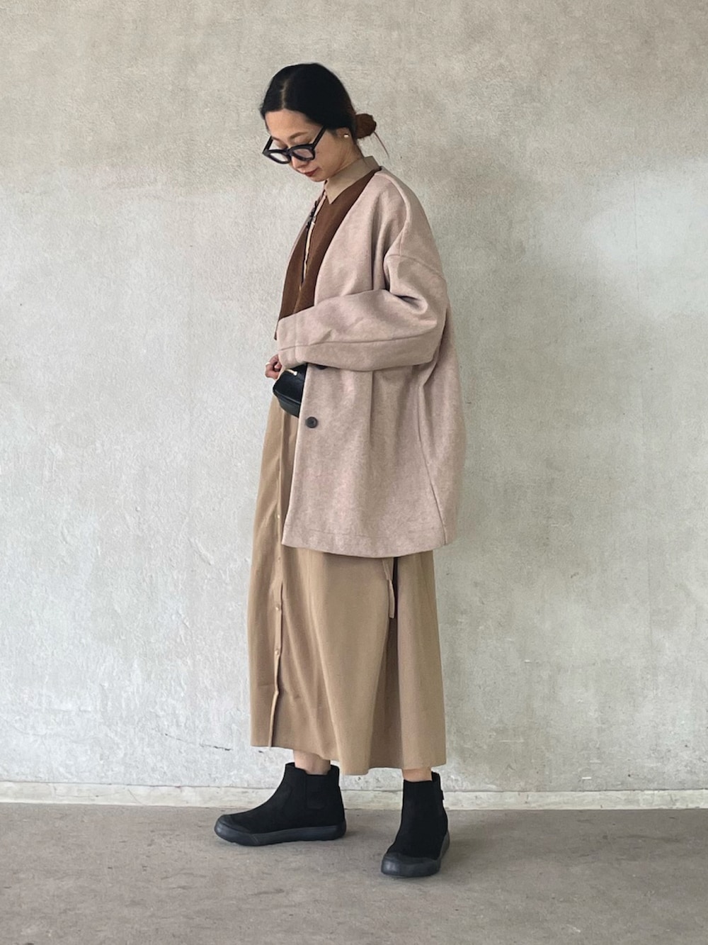 ピンク系のノーカラーコート、ベージュ系のワンピース、ブラック系のブーツを着用したレディースの秋コーディネートの3枚目の写真