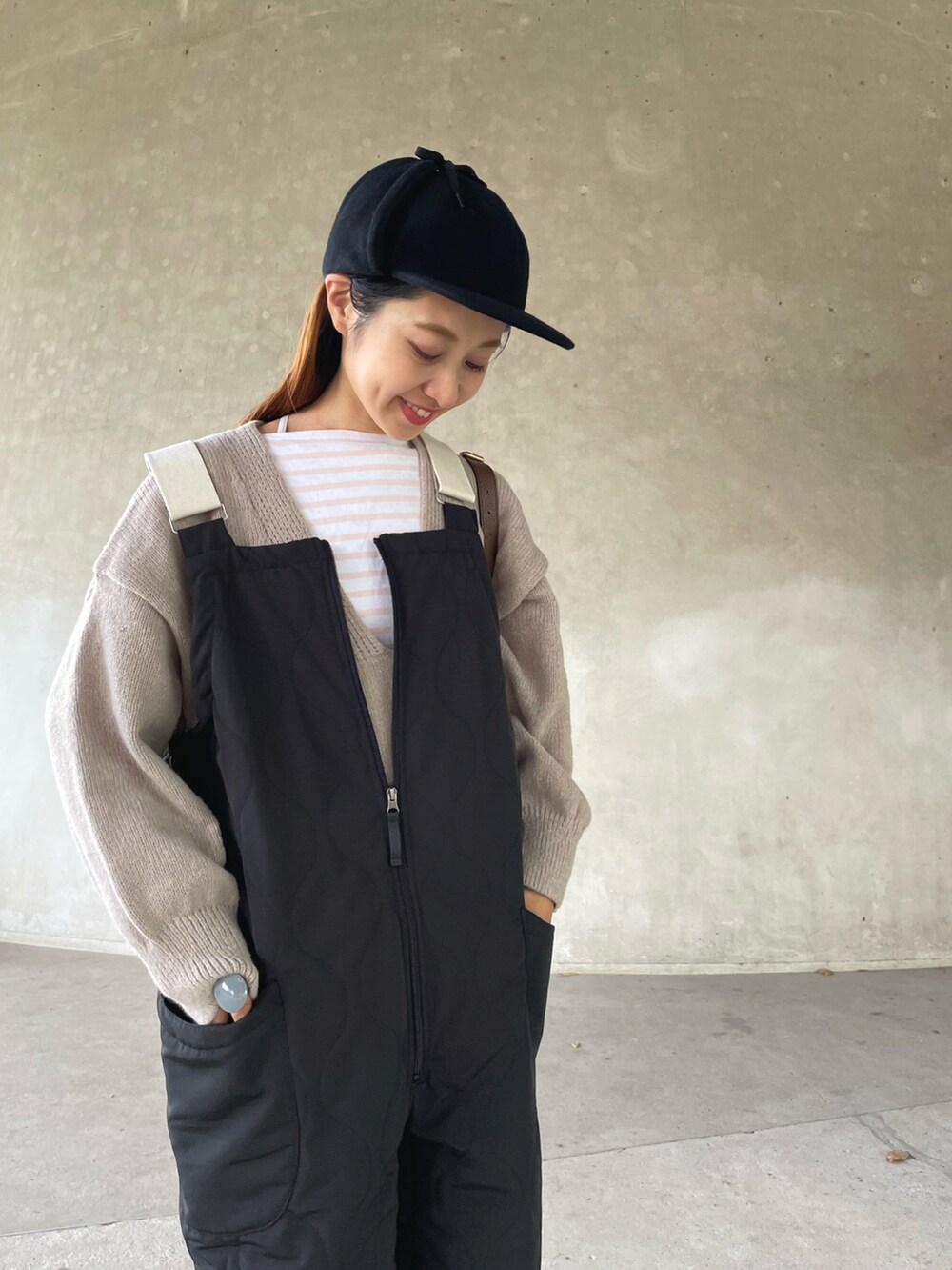 ベージュ系のニット/セーター、ブラック系のサロペット/オーバーオール、ベージュ系のブーツを着用したレディースの秋コーディネートの4枚目の写真