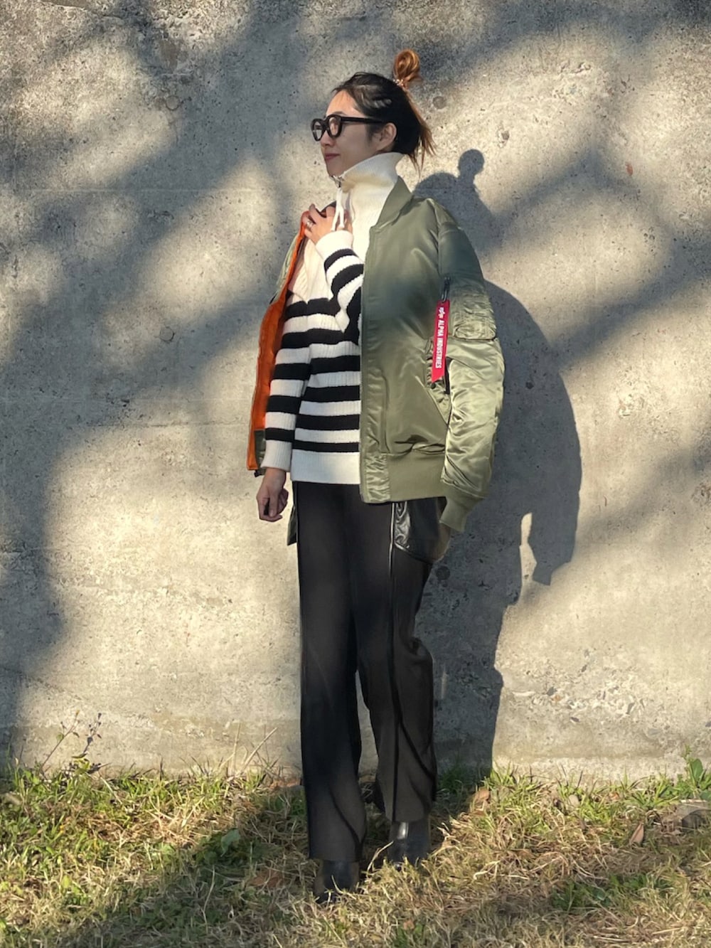 グリーン系のMA-1、ホワイト系のニット/セーター、ブラック系のその他パンツを着用したレディースの冬コーディネートの5枚目の写真