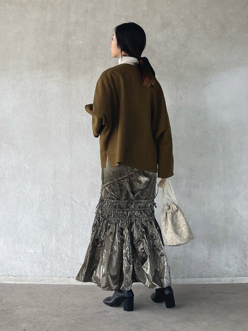 グリーン系のTシャツ/カットソー、シルバー系のスカートを着用したレディースの冬コーディネートの2枚目の写真