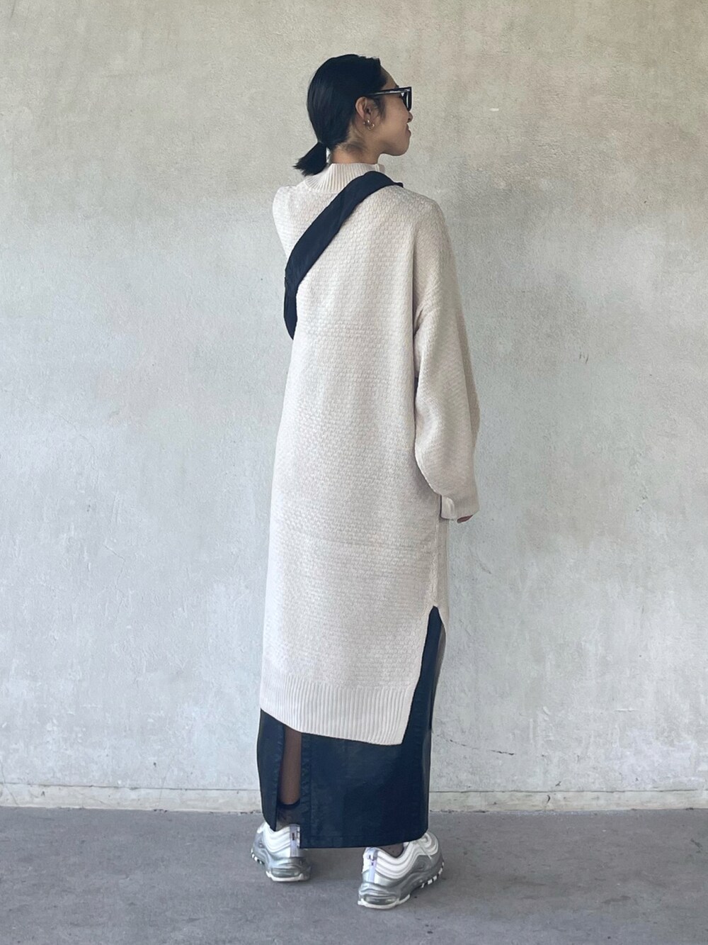 ホワイト系のワンピース、ブラック系のスカート、ブラック系のショルダーバッグを着用したレディースの秋コーディネートの2枚目の写真