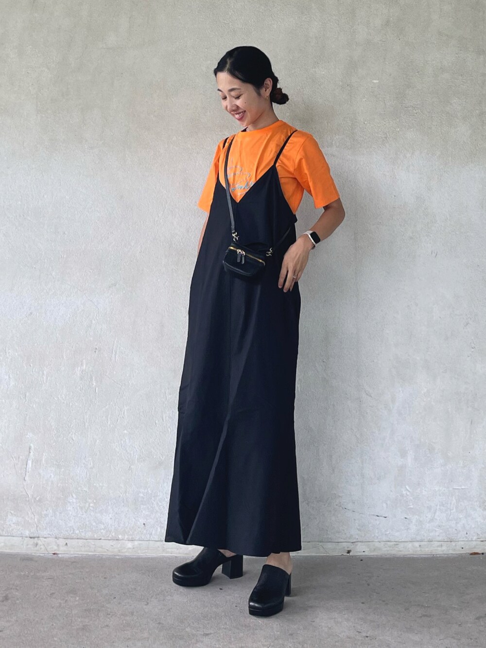 ブラック系のワンピース、オレンジ系のTシャツ/カットソー、ブラック系のサンダルを着用したレディースの夏コーディネートの5枚目の写真