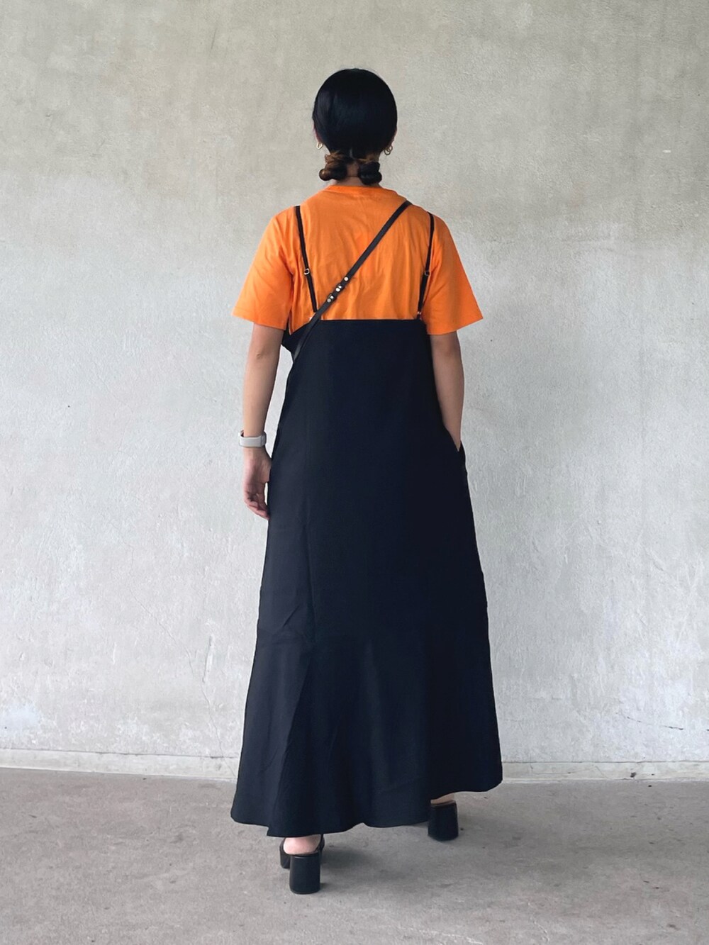 ブラック系のワンピース、オレンジ系のTシャツ/カットソー、ブラック系のサンダルを着用したレディースの夏コーディネートの3枚目の写真