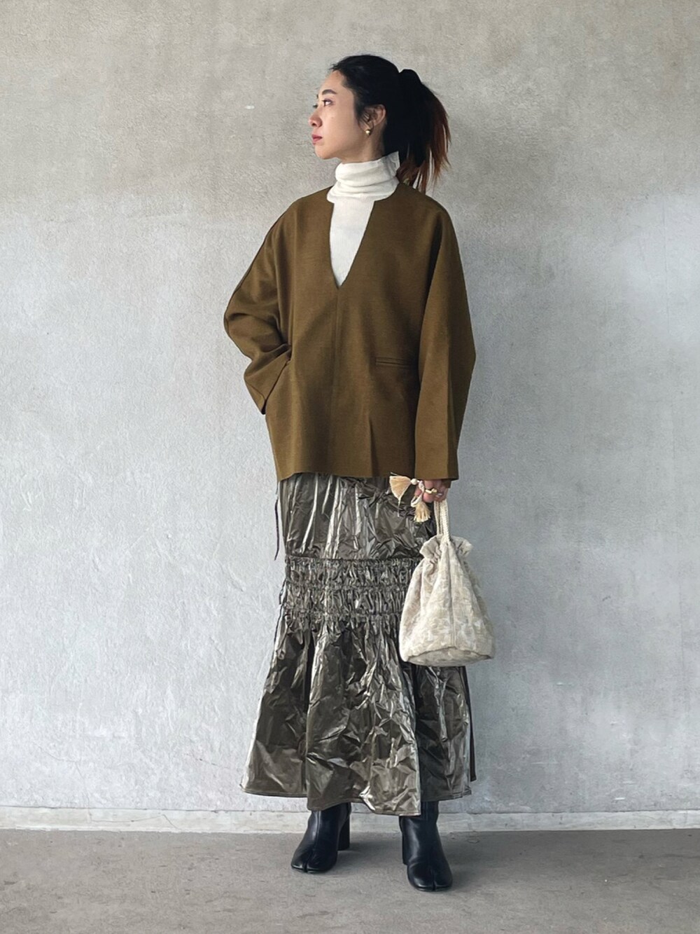 グリーン系のTシャツ/カットソー、シルバー系のスカートを着用したレディースの冬コーディネートの4枚目の写真