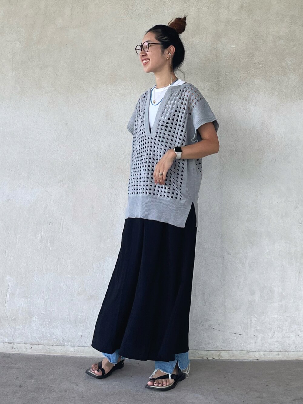 グレー系のベスト、ブラック系のワンピース、ブラック系のサンダルを着用したレディースの夏コーディネートの3枚目の写真