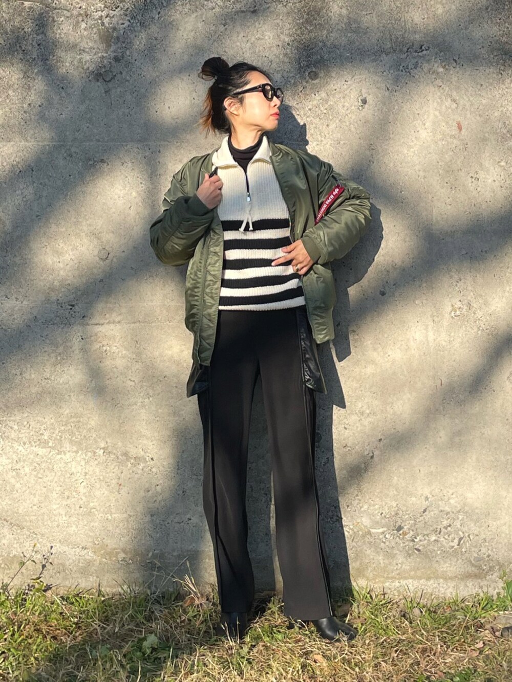 グリーン系のMA-1、ホワイト系のニット/セーター、ブラック系のその他パンツを着用したレディースの冬コーディネートの3枚目の写真