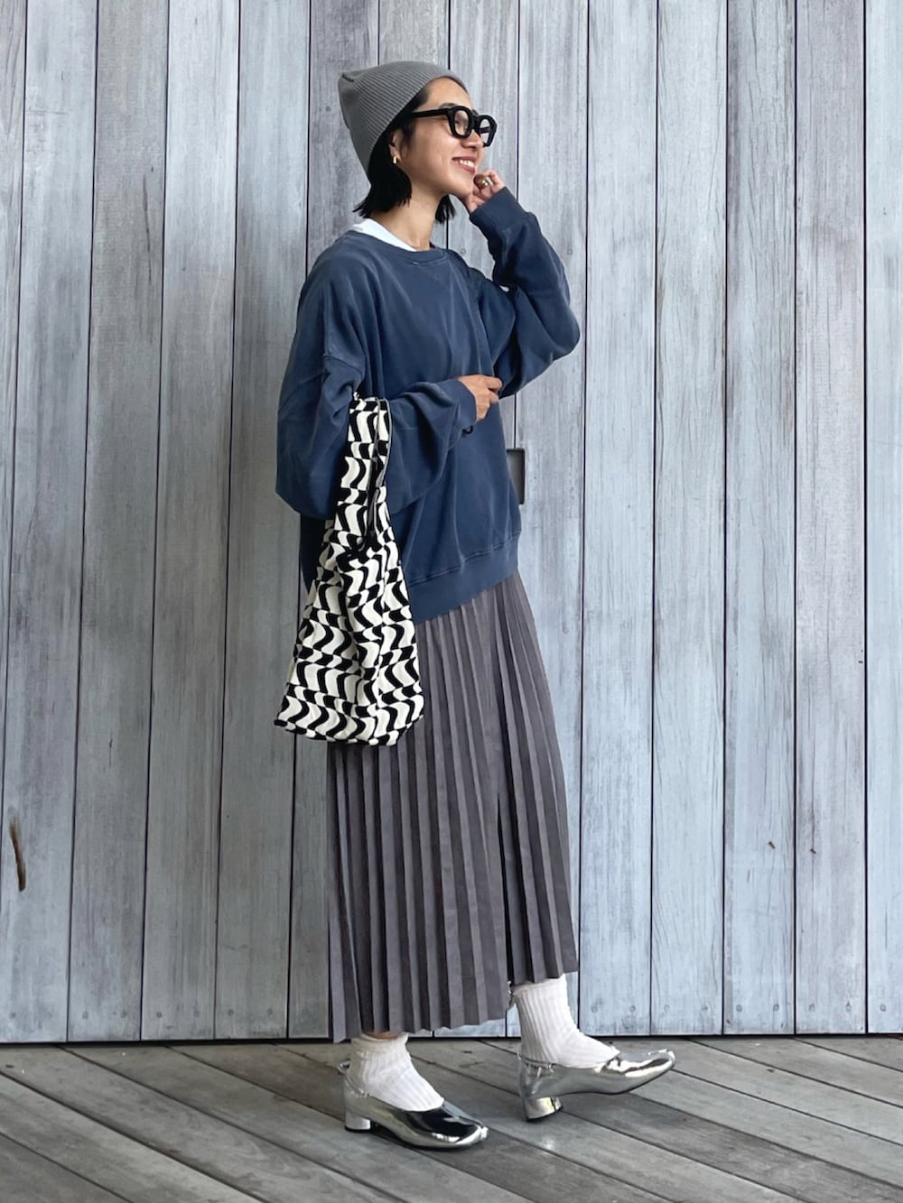 ブルー系のスウェット、グレー系のスカート、ブラック系のトートバッグを着用したレディースの秋コーディネートの2枚目の写真