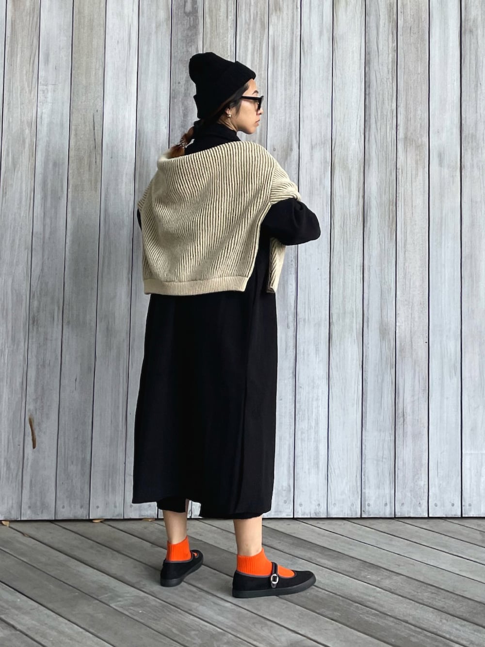 ブラック系のチェスターコート、ブラック系のワンピース、グリーン系のニット/セーターを着用したレディースの秋コーディネートの2枚目の写真