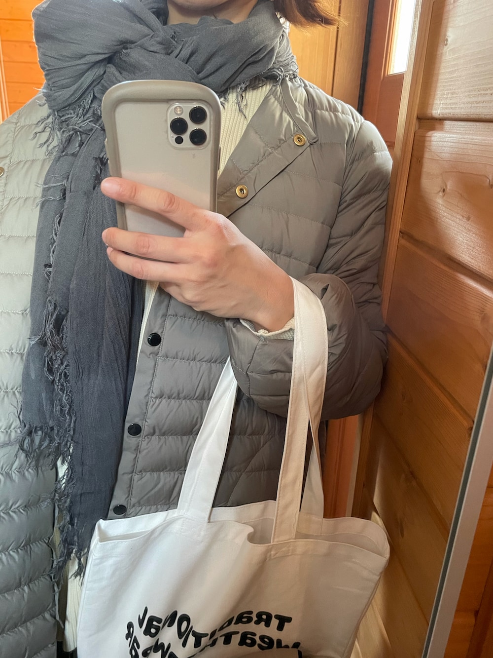 グレー系のダウンジャケット/コート、ベージュ系のニット/セーター、ホワイト系のトートバッグを着用したレディースの秋コーディネートの4枚目の写真