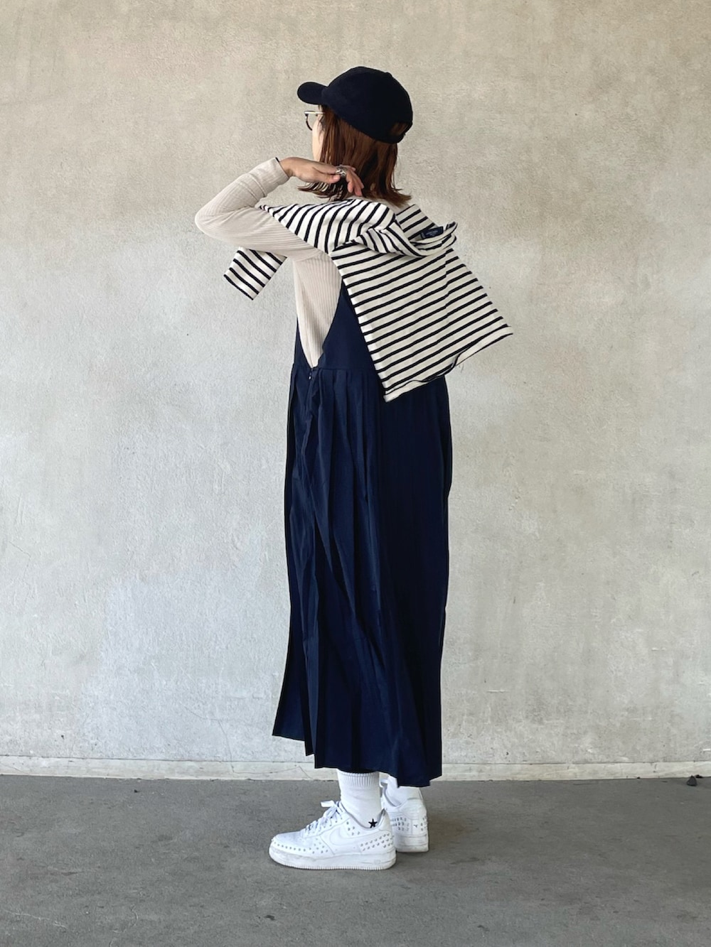 ホワイト系のTシャツ/カットソー、ベージュ系のニット/セーター、ブルー系のジャンパースカートを着用したレディースの冬コーディネートの3枚目の写真