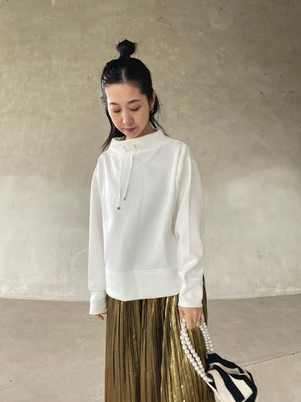 ホワイト系のスウェット、ゴールド系のスカート、ホワイト系のショルダーバッグを着用したレディースの春コーディネートの3枚目の写真