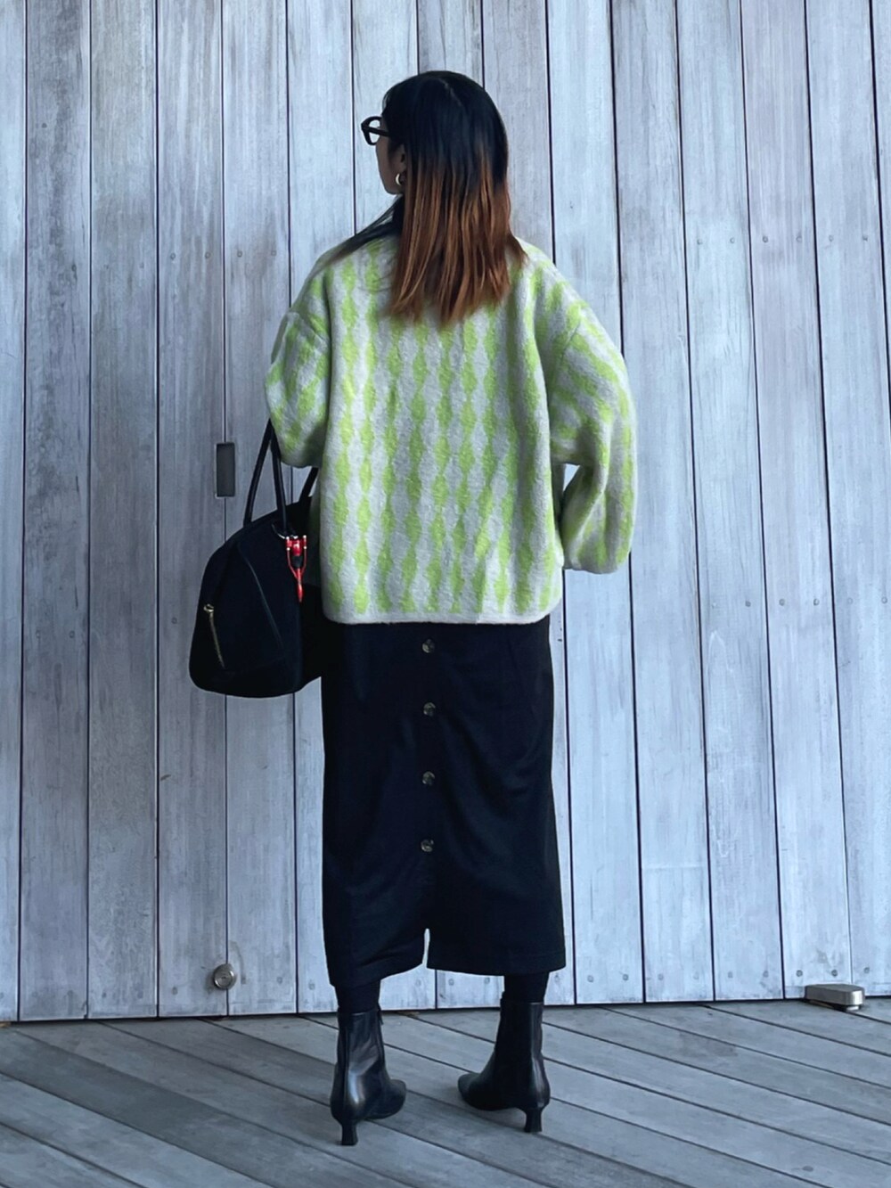 グリーン系のカーディガン/ボレロ、ブラック系のブーツ、ブラック系のサロペット/オーバーオールを着用したレディースの秋コーディネートの4枚目の写真