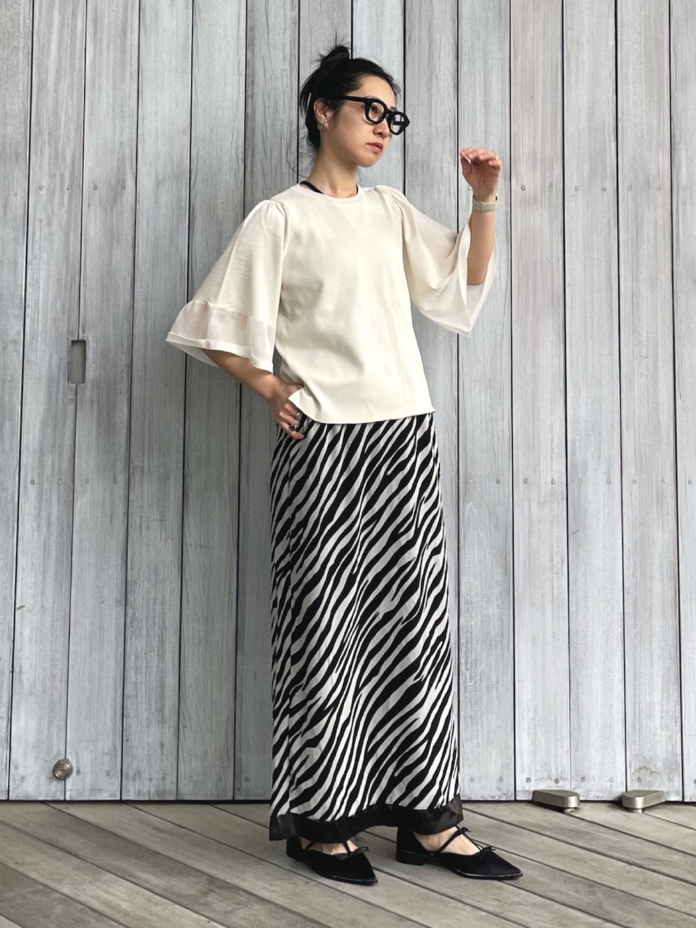 ホワイト系のニット/セーター、ホワイト系のスカート、ブラック系のパンプスを着用したレディースの春コーディネートの2枚目の写真