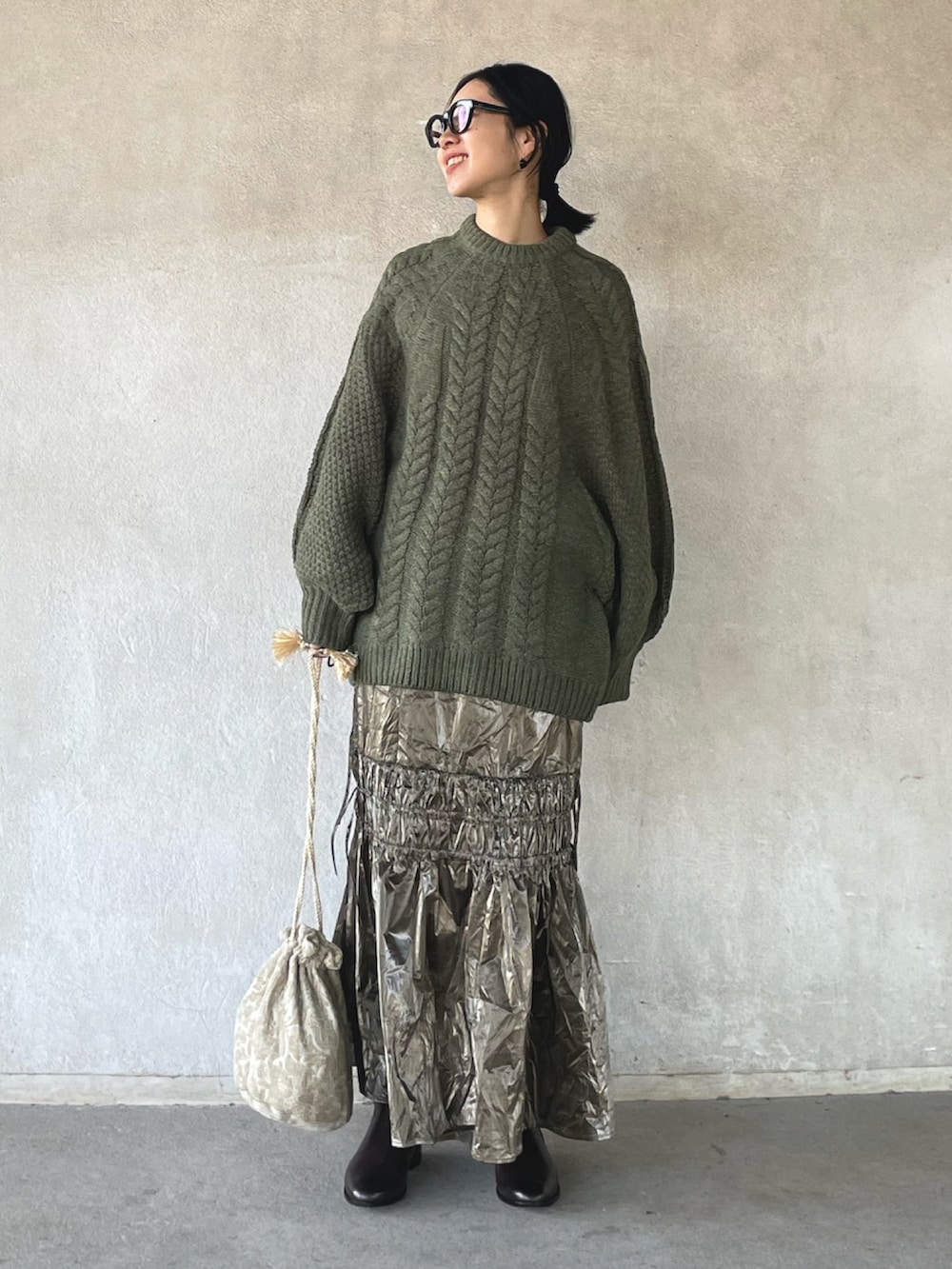 ブラック系のステンカラーコート、グリーン系のニット/セーター、シルバー系のスカートを着用したレディースの冬コーディネートの3枚目の写真