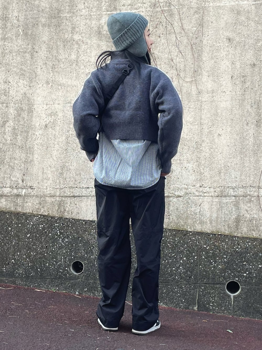 グレー系のニット/セーター、ホワイト系のスニーカー、グレー系のニットキャップ/ビーニーを着用したレディースの冬コーディネートの2枚目の写真