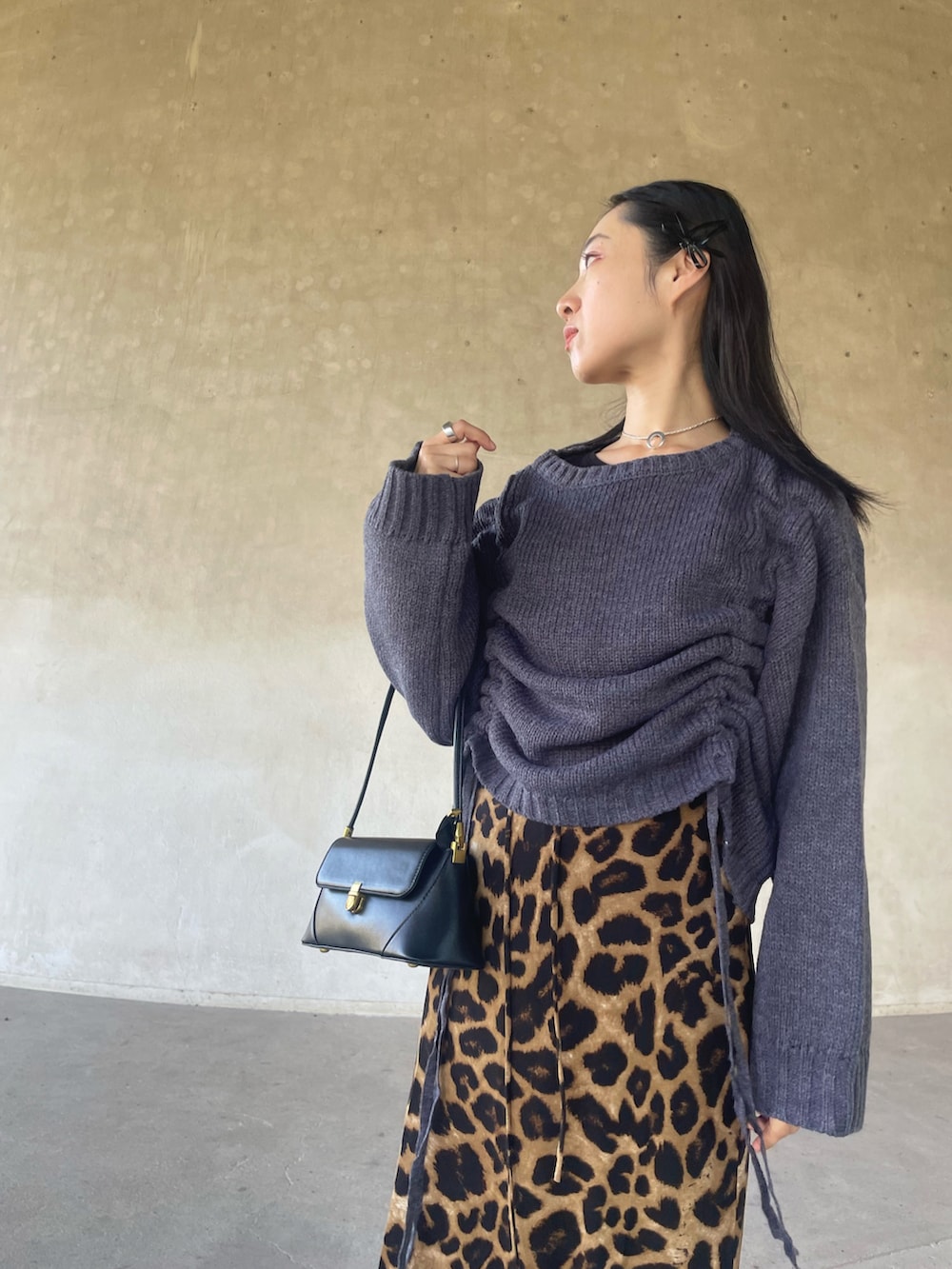 グレー系のニット/セーター、ベージュ系のスカート、ブラック系のハンドバッグを着用したレディースの秋コーディネートの5枚目の写真