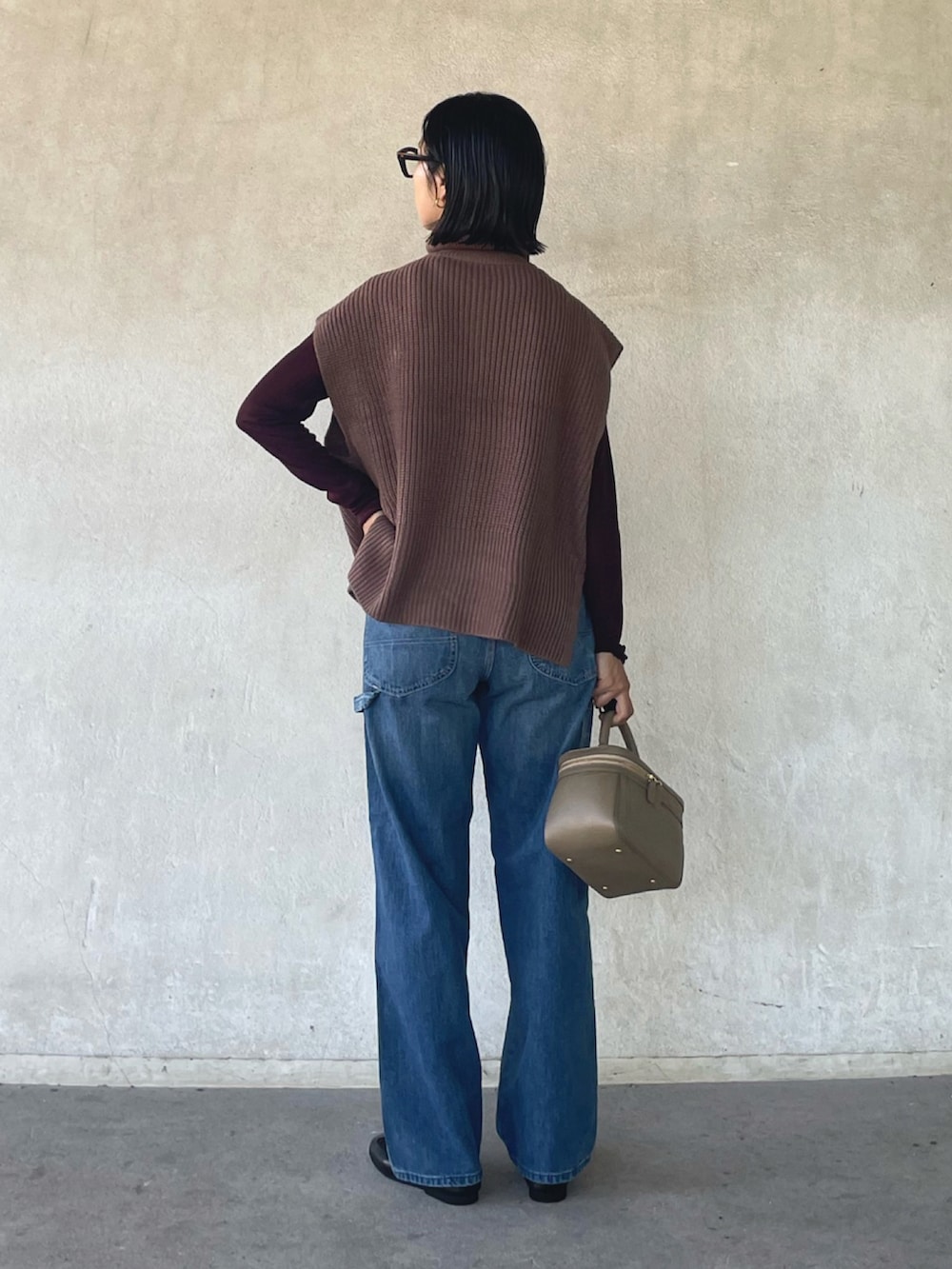 ブラウン系のベスト、ブラウン系のTシャツ/カットソー、ブルー系のデニムパンツを着用したレディースの秋コーディネートの5枚目の写真