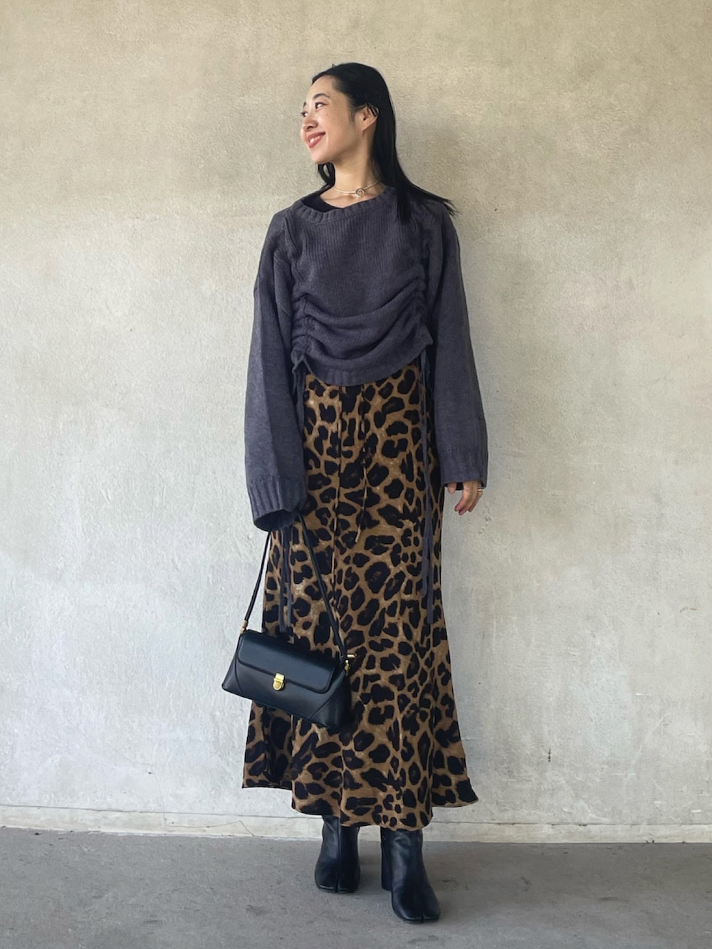 グレー系のニット/セーター、ベージュ系のスカート、ブラック系のハンドバッグを着用したレディースの秋コーディネートの4枚目の写真