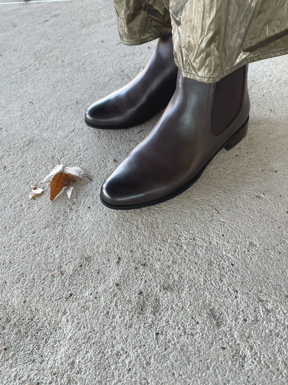 ブラック系のステンカラーコート、グリーン系のニット/セーター、シルバー系のスカートを着用したレディースの冬コーディネートの4枚目の写真