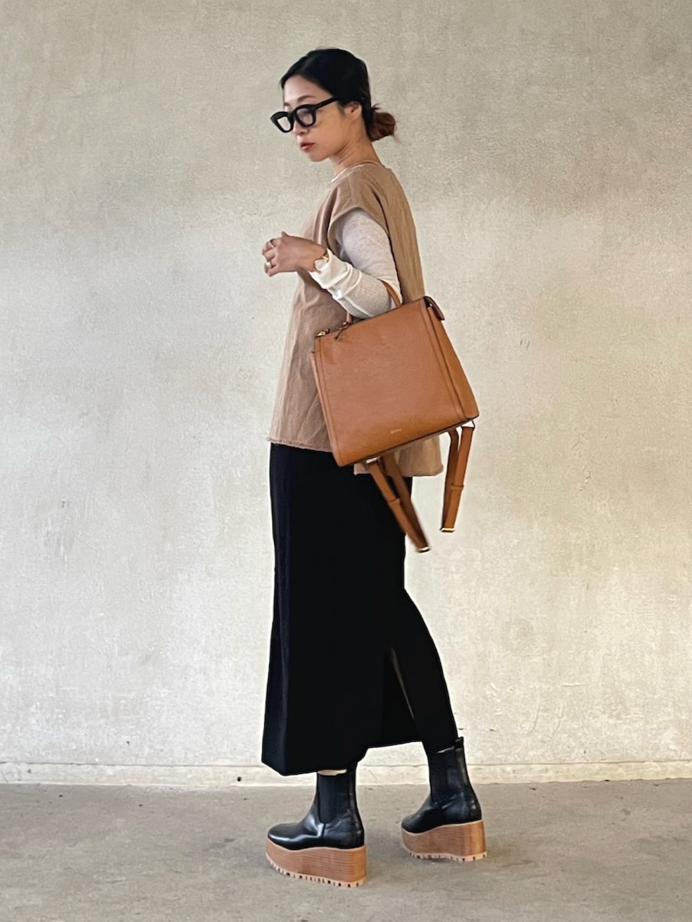 ベージュ系のベスト、ホワイト系のTシャツ/カットソー、イエロー系のバックパック/リュックを着用したレディースの秋コーディネートの5枚目の写真