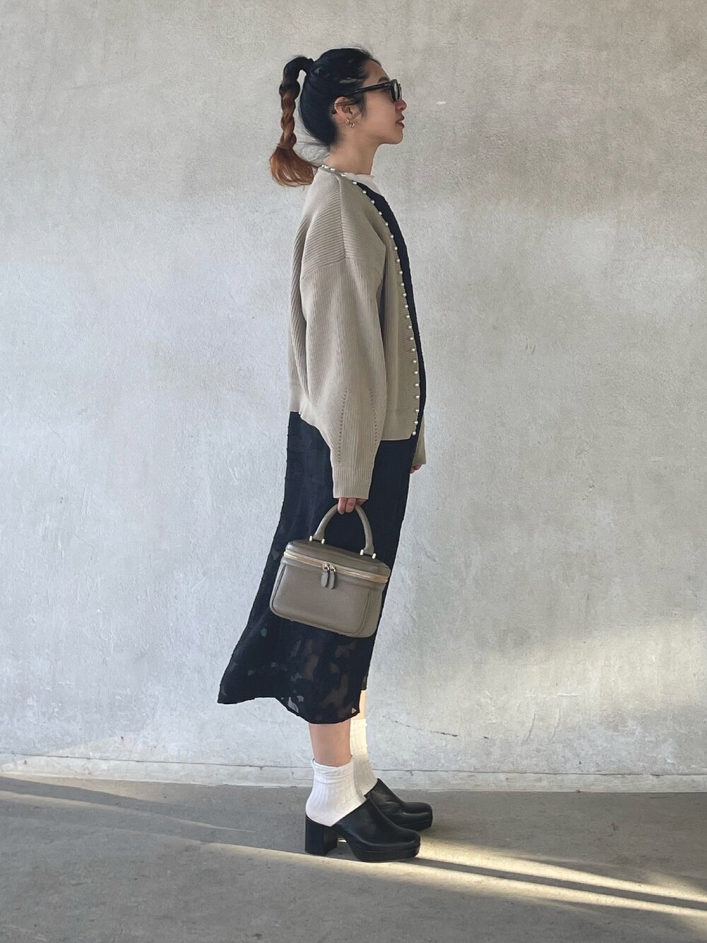 ベージュ系のカーディガン/ボレロ、ブラック系のワンピース、ブラック系のサンダルを着用したレディースの春コーディネートの3枚目の写真