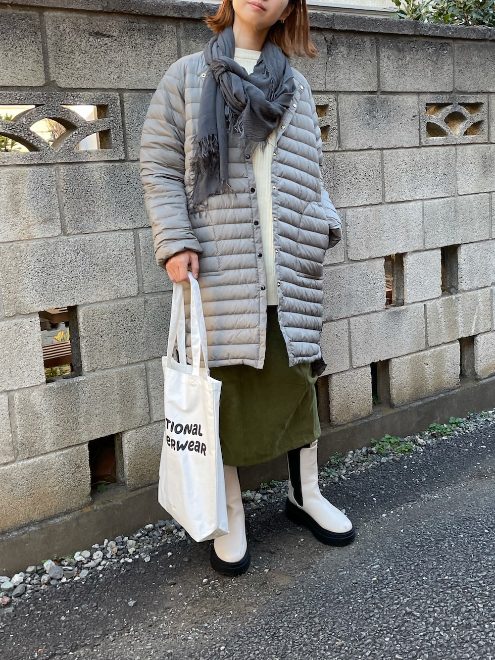 グレー系のダウンジャケット/コート、ベージュ系のニット/セーター、ホワイト系のトートバッグを着用したレディースの秋コーディネートの3枚目の写真