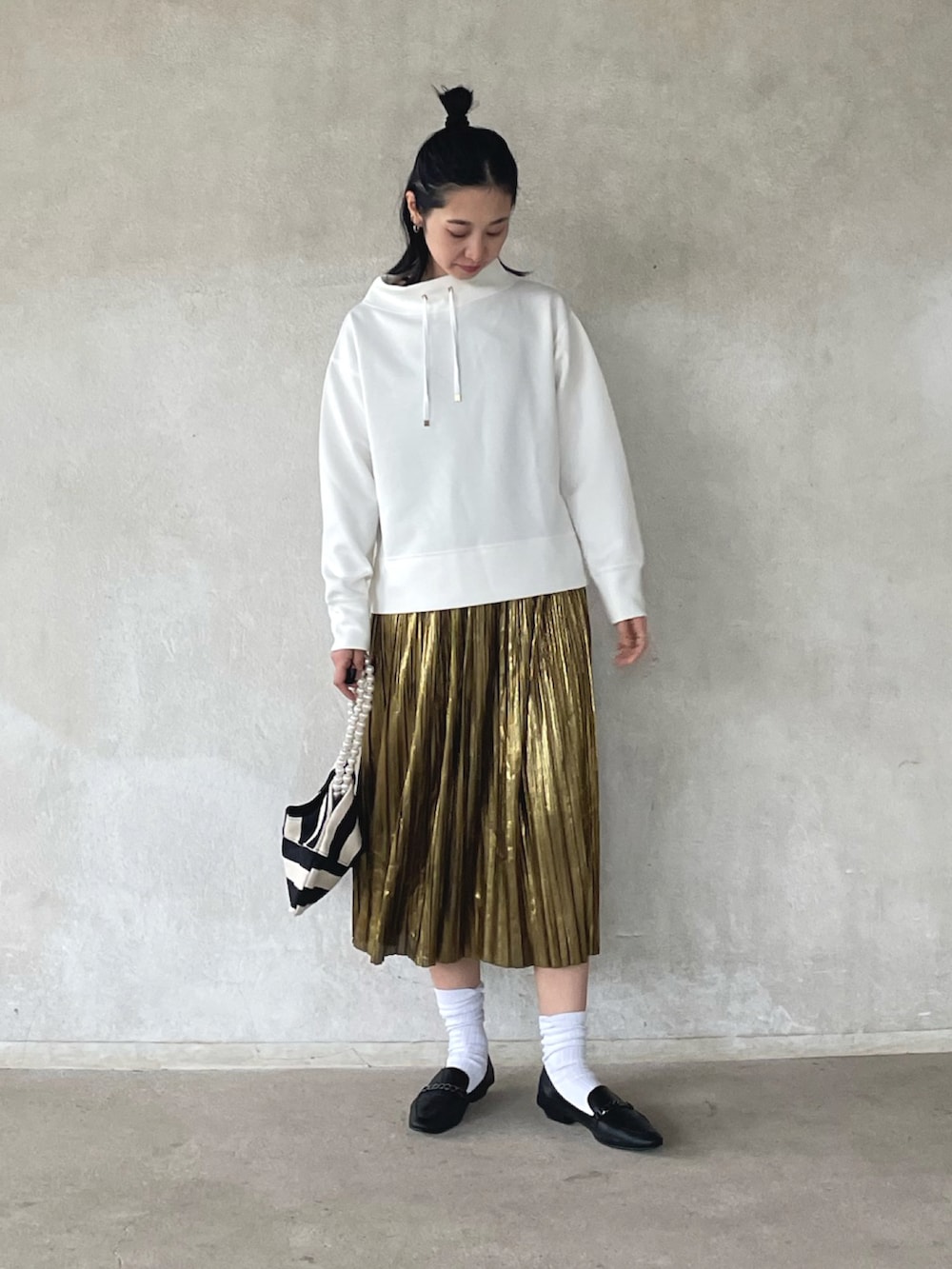ホワイト系のスウェット、ゴールド系のスカート、ホワイト系のショルダーバッグを着用したレディースの春コーディネートの2枚目の写真