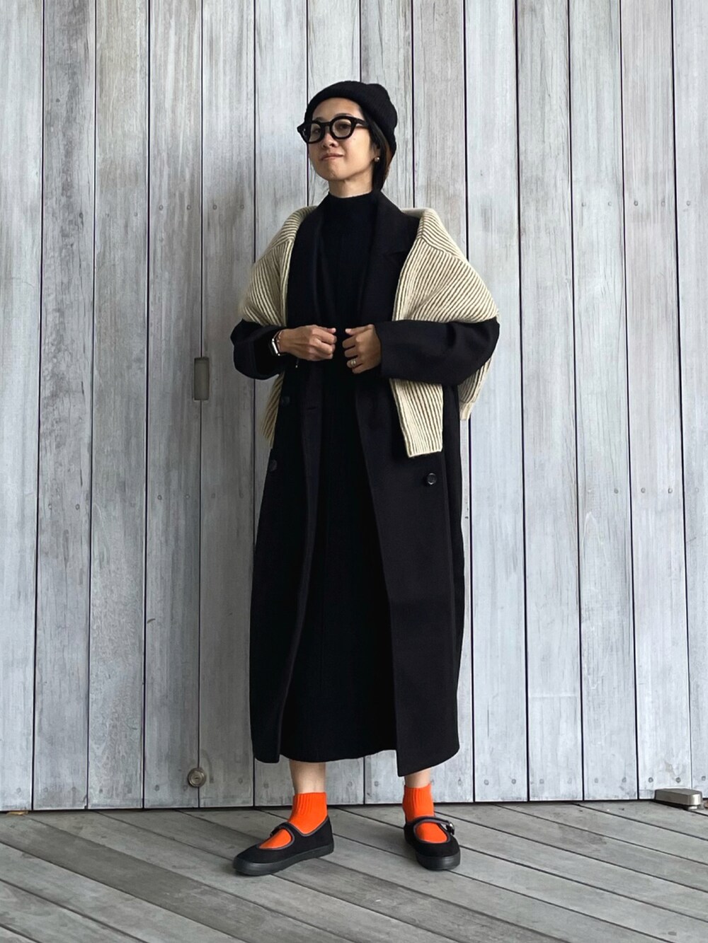 ブラック系のチェスターコート、ブラック系のワンピース、グリーン系のニット/セーターを着用したレディースの秋コーディネートの5枚目の写真