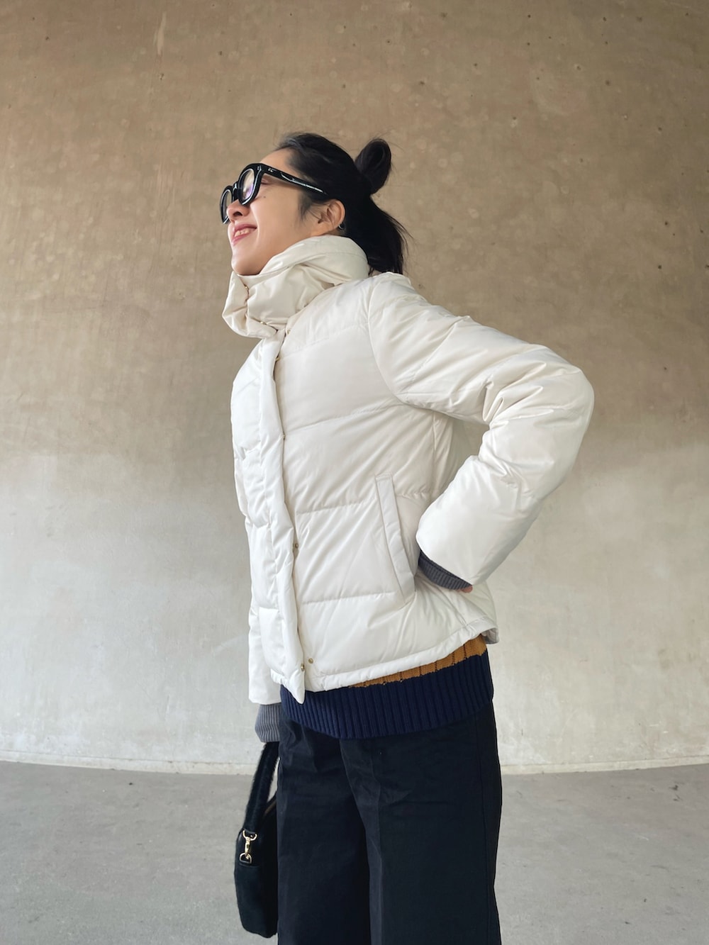 ホワイト系のダウンジャケット/コート、ブルー系のベスト、ブラック系のデニムパンツを着用したレディースの冬コーディネートの3枚目の写真