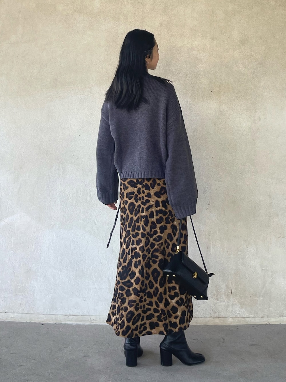 グレー系のニット/セーター、ベージュ系のスカート、ブラック系のハンドバッグを着用したレディースの秋コーディネートの3枚目の写真