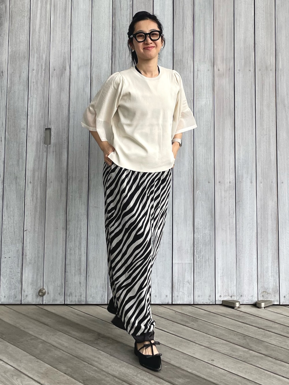 ホワイト系のニット/セーター、ホワイト系のスカート、ブラック系のパンプスを着用したレディースの春コーディネートの3枚目の写真