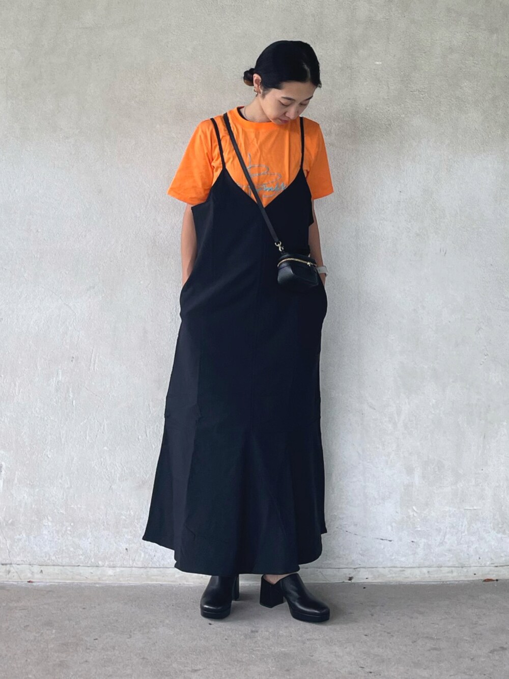 ブラック系のワンピース、オレンジ系のTシャツ/カットソー、ブラック系のサンダルを着用したレディースの夏コーディネートの4枚目の写真