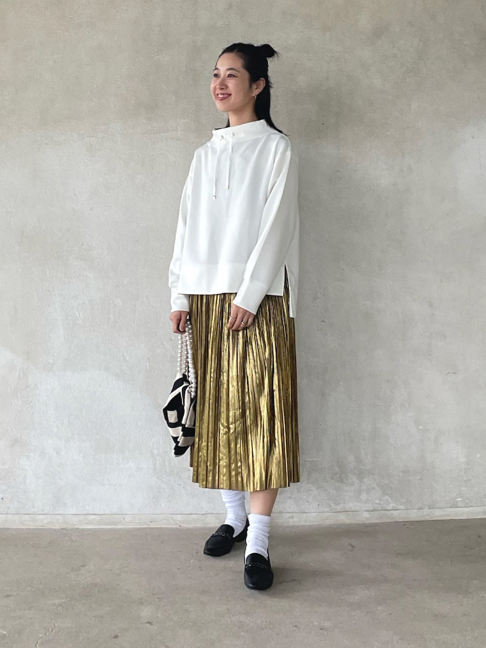 ホワイト系のスウェット、ゴールド系のスカート、ホワイト系のショルダーバッグを着用したレディースの春コーディネートの5枚目の写真