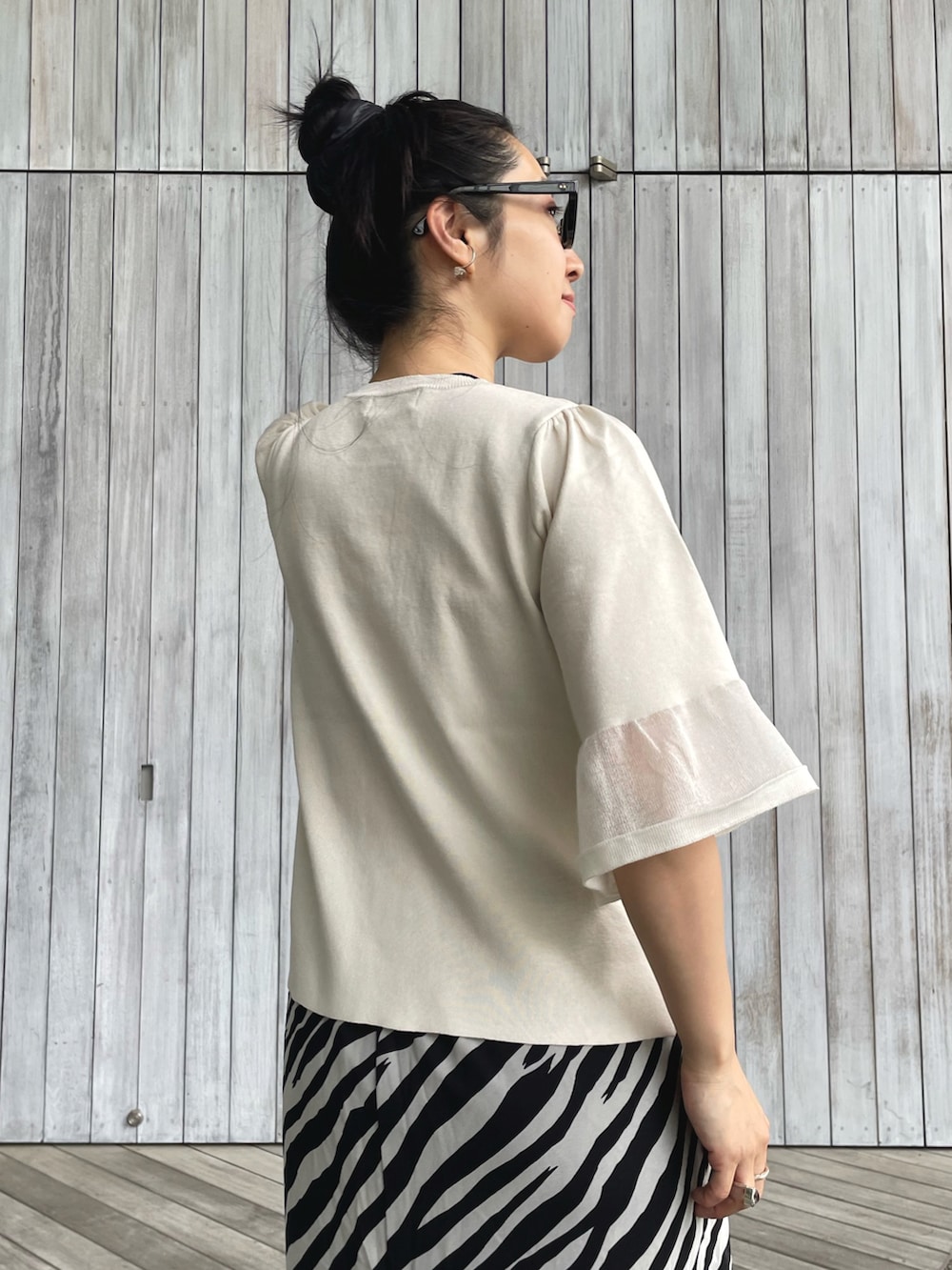 ホワイト系のニット/セーター、ホワイト系のスカート、ブラック系のパンプスを着用したレディースの春コーディネートの4枚目の写真