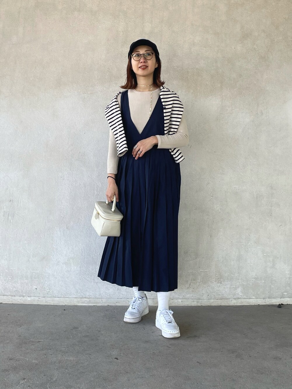 ホワイト系のTシャツ/カットソー、ベージュ系のニット/セーター、ブルー系のジャンパースカートを着用したレディースの冬コーディネートの5枚目の写真