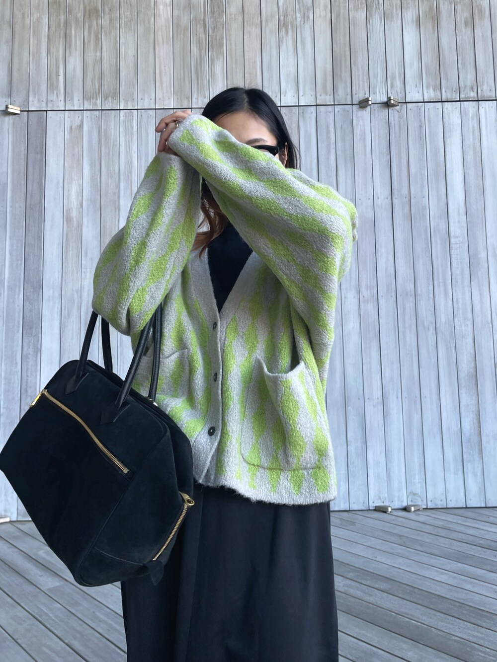 グリーン系のカーディガン/ボレロ、ブラック系のブーツ、ブラック系のサロペット/オーバーオールを着用したレディースの秋コーディネートの5枚目の写真