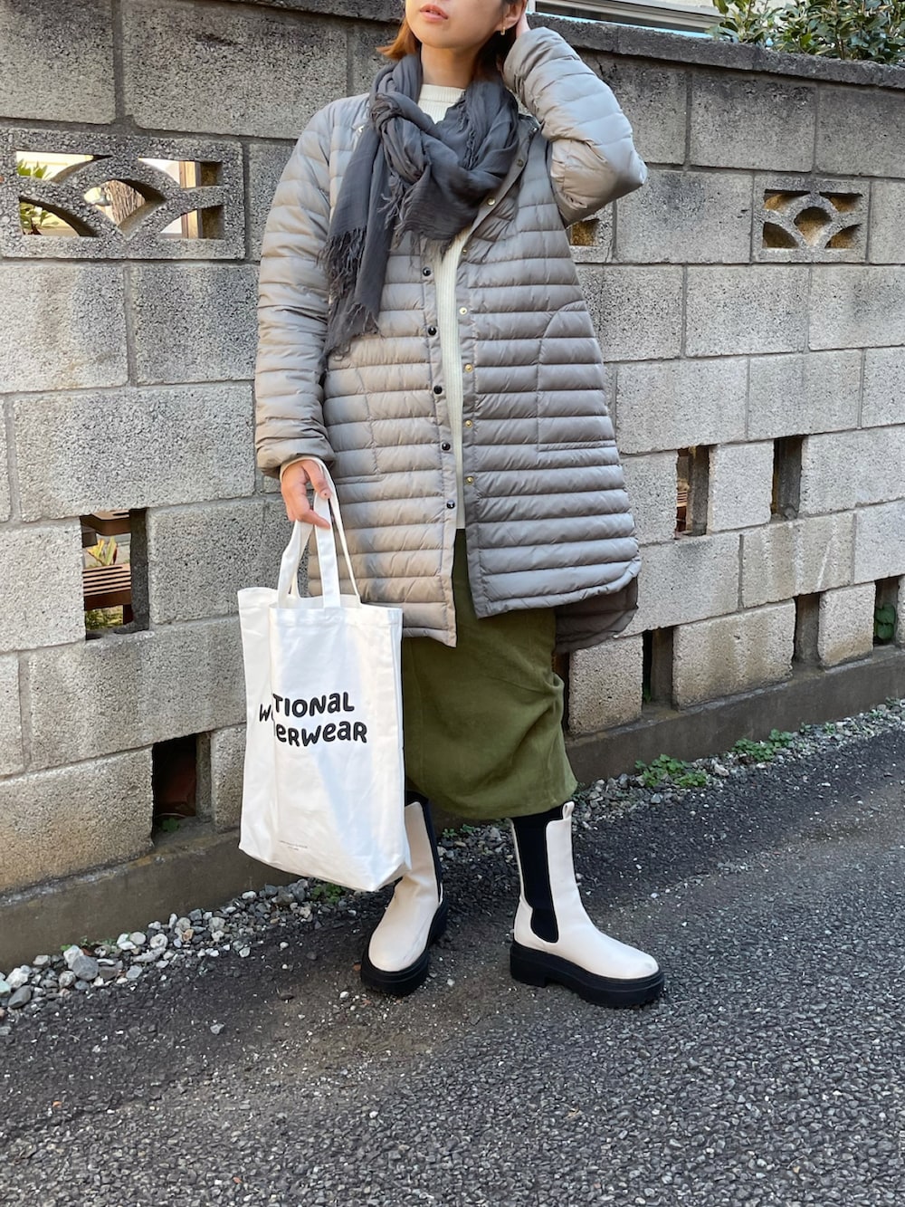 グレー系のダウンジャケット/コート、ベージュ系のニット/セーター、ホワイト系のトートバッグを着用したレディースの秋コーディネートの2枚目の写真