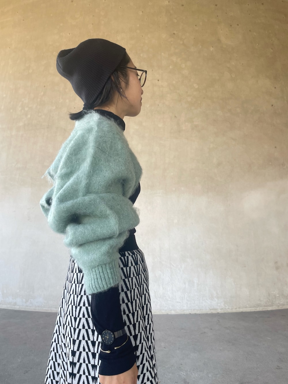 グリーン系のニット/セーター、ホワイト系のスカート、ブラック系のブーツを着用したレディースの冬コーディネートの3枚目の写真