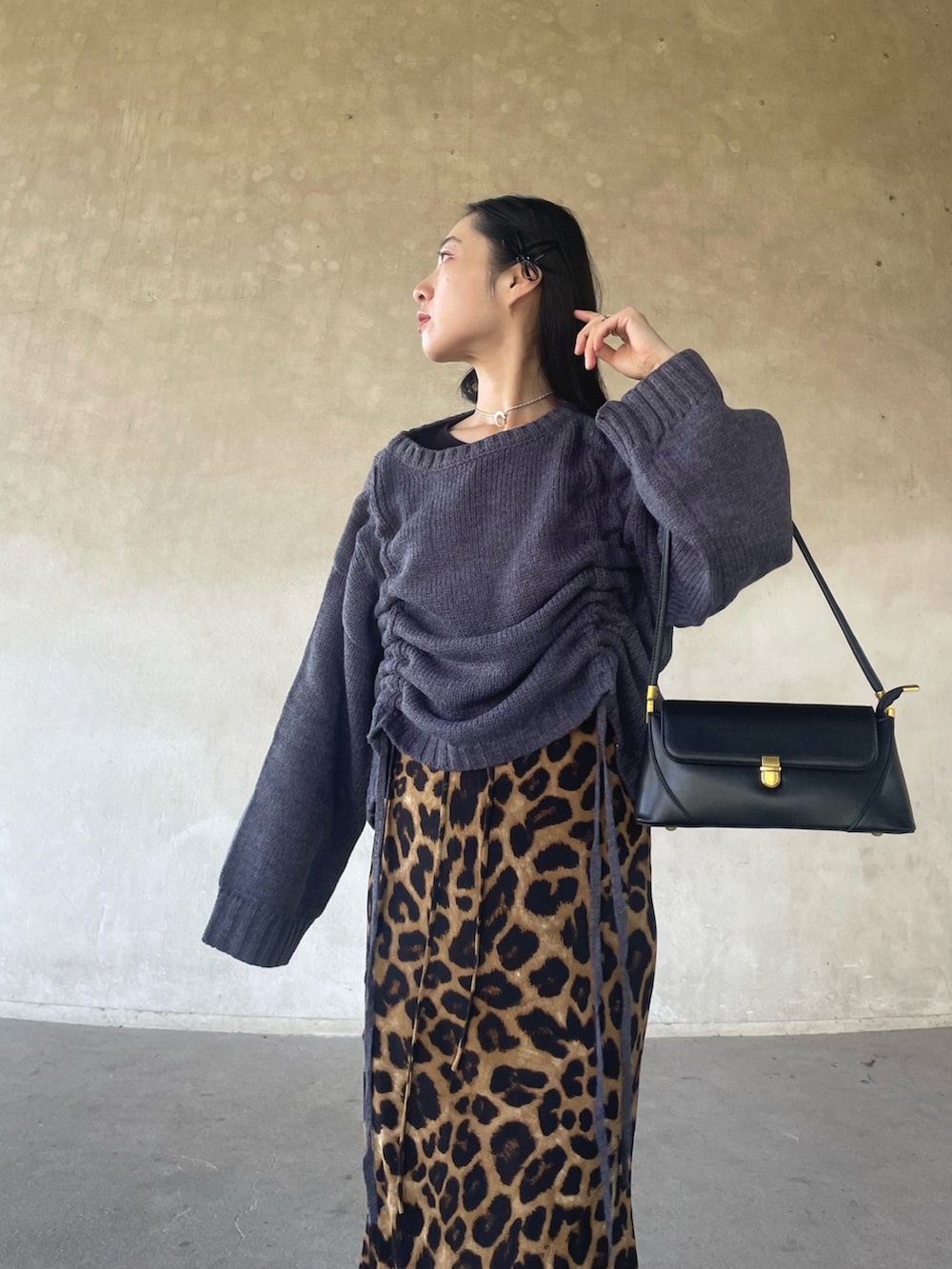 グレー系のニット/セーター、ベージュ系のスカート、ブラック系のハンドバッグを着用したレディースの秋コーディネートの2枚目の写真