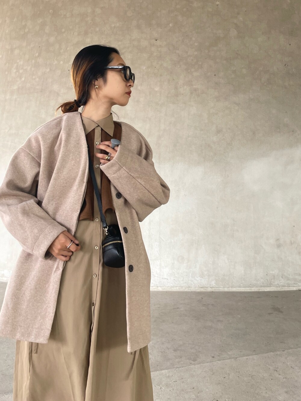 ピンク系のノーカラーコート、ベージュ系のワンピース、ブラック系のブーツを着用したレディースの秋コーディネートの5枚目の写真
