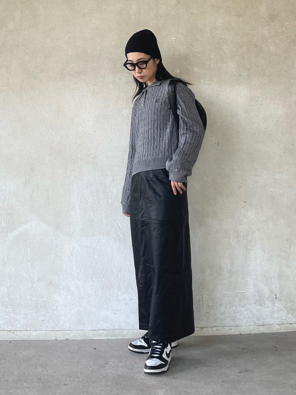 グレー系のニット/セーター、ブラック系のスカート、ホワイト系のスニーカーを着用したレディースの秋コーディネートの2枚目の写真